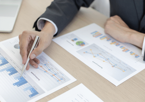 Illustration d'une main avec un crayon en train de lire des graphiques financiers